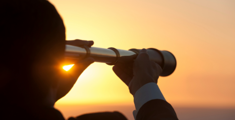 Immagine decorativa. Persona che guarda in un binocolo al tramonto